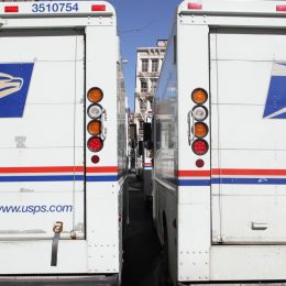 The rear doors of two USPS mail delivery trucks