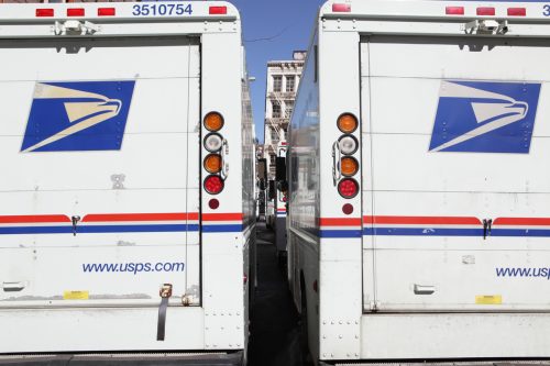 The rear doors of two USPS mail delivery trucks