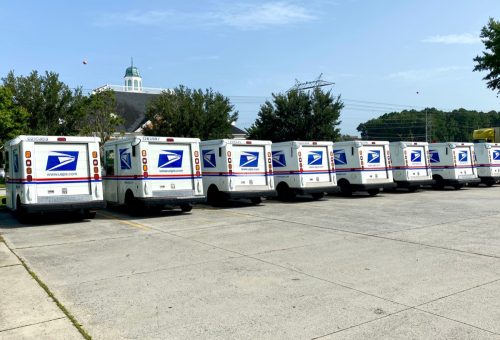USPS building and trucks in the sunshine lined up