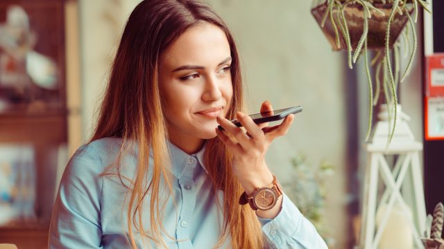 A young woman talking to her phone's virtual assistant