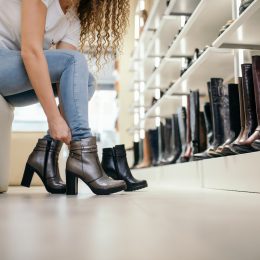 Close up of a woman bending over to try on boots in a shoe store