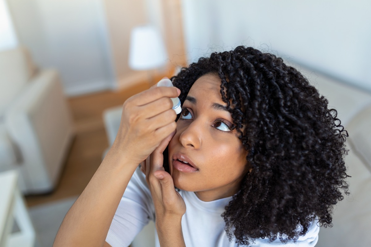 Black woman suffering from dry eyes using eye drops