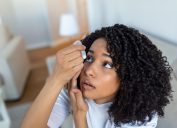 Black woman suffering from dry eyes using eye drops