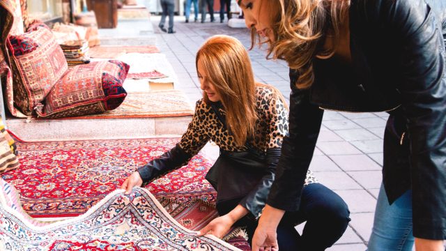 Two women looking at a rug in a store