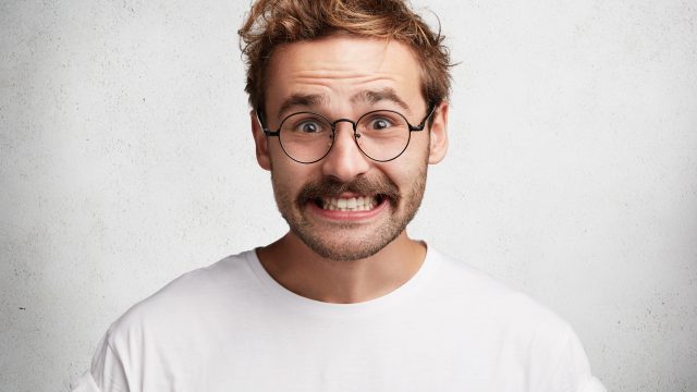 Man in glasses smiling awkwardly