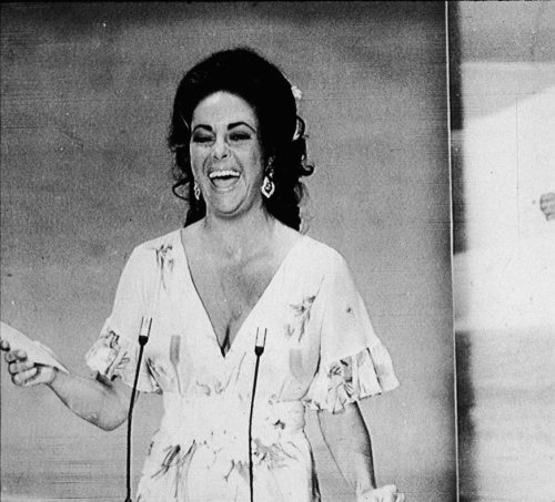 Elizabeth Taylor laughs at streaker who runs across the stage.