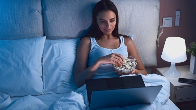 Woman Eating Popcorn in Bed