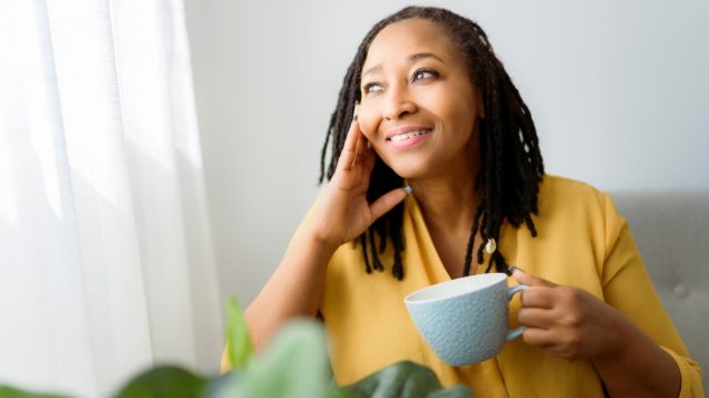 Woman smiling with a cup of coffee in her hand.