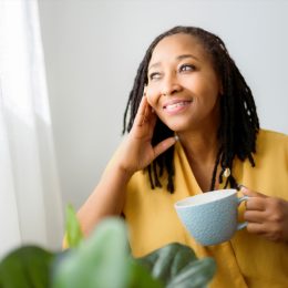 Woman smiling with a cup of coffee in her hand.