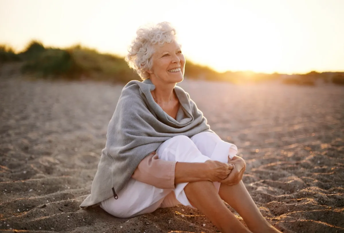 Người phụ nữ ngồi trên bãi biển hạnh phúc.