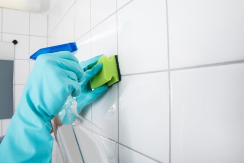 Cleaning Service Professional Wearing Gloves Cleaning The Tiled Wall Using Sponge And Spray Bottle