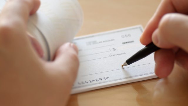 A close-up of someone beginning to write a check