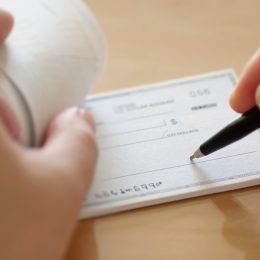 A close-up of someone beginning to write a check
