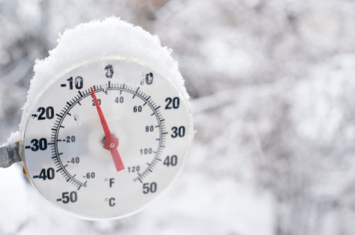 A thermometer showing freezing temperatures and falling snow in Yellowknife, Northwest Territories. Blurred snow background for good copy space image right. Close up.