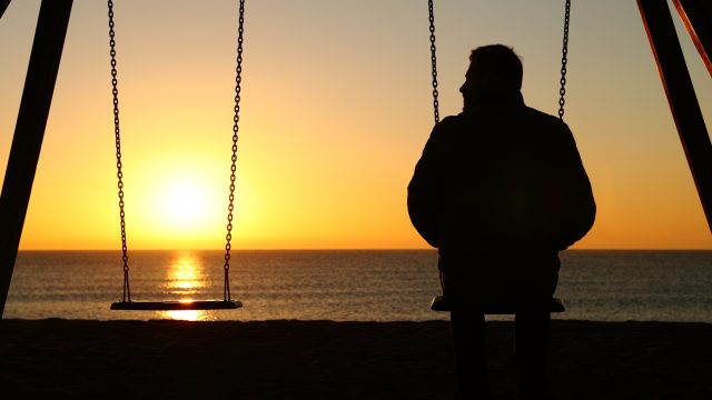 man next to an empty swing during sunset