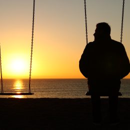 man next to an empty swing during sunset