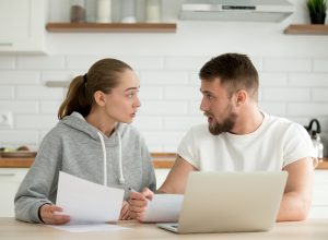 Young couple arguing about bills or document at home kitchen