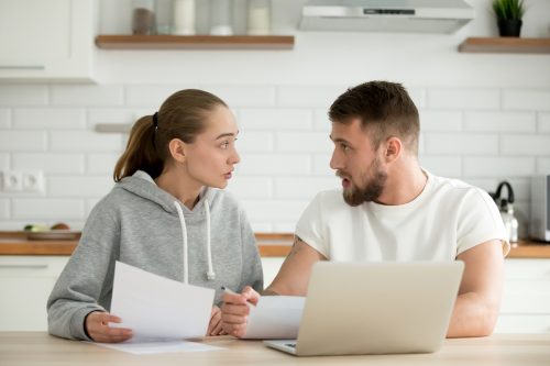 Young couple arguing about bills or document at home kitchen