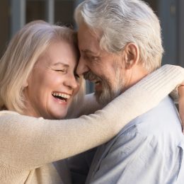 Happy mature couple in love embracing, laughing grey haired husband and wife with closed eyes