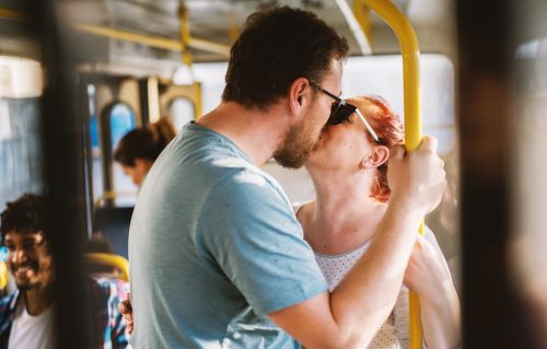 Happy mature couple kissing in a public transportation.
