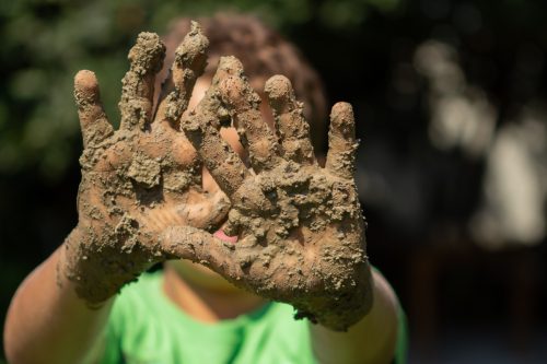child showing dirty muddy hands outside
