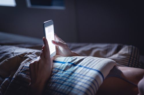 woman using her phone late at night while in bed