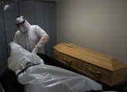 Mortuary workers put the body inside a coffin at funeral home.