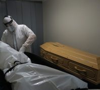 Mortuary workers put the body inside a coffin at funeral home.