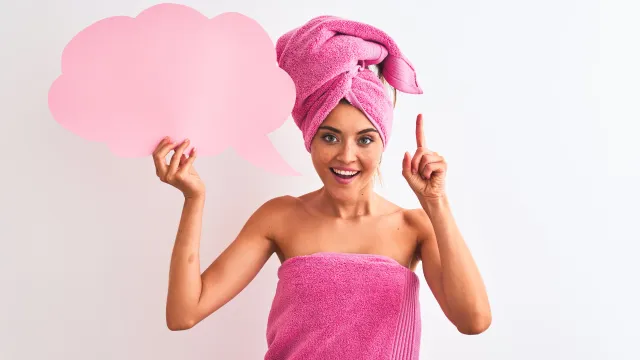 woman in a towel holding up a paper thought bubble