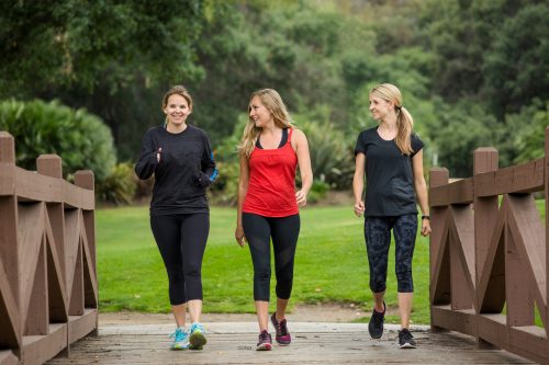 Three young ish women in athletic wear walking over a bridge