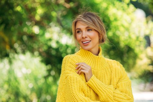 Smiling young woman outdoors in a bright yellow sweater