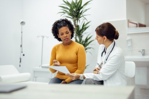 Woman sitting in a doctor's office talking with physician.