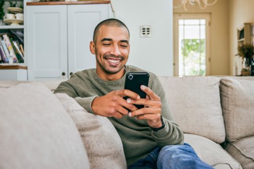 young man texting at home on the couch