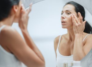 Woman looking at her skin in a mirror.