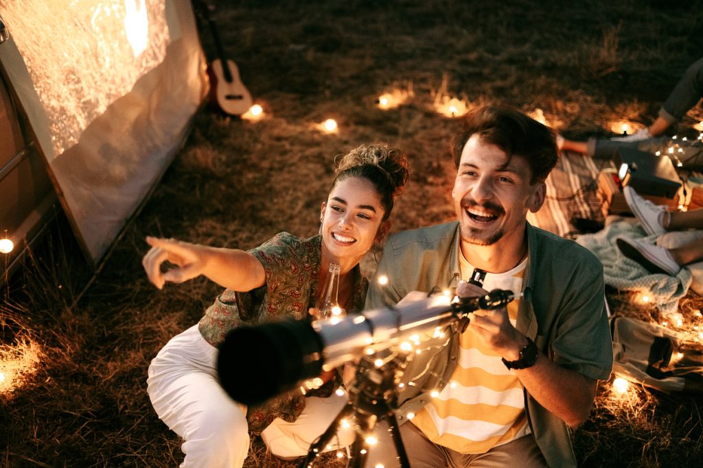 Couple stargazing together with a astronomical telescope while being on a romantic date