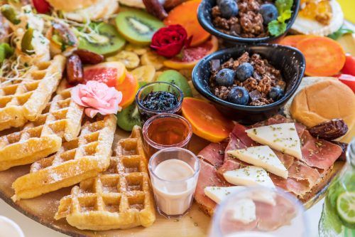 A delicious gourmet breakfast charcuterie board with waffles, fruits, and oatmeal