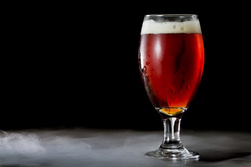 closeup of an irish red ale served in a chalice over a black background