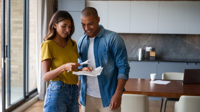 couple at home reading a letter in the mail and looking happy - lifestyle concepts