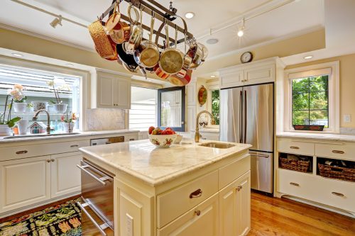 White kitchen with white granite tops, island and hanging pot rack