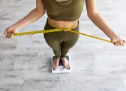 woman measuring waist while standing on scale