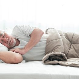 Older asian man sleeping comfortably in bed with curtain open
