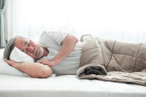 Older asian man sleeping comfortably in bed with curtain open