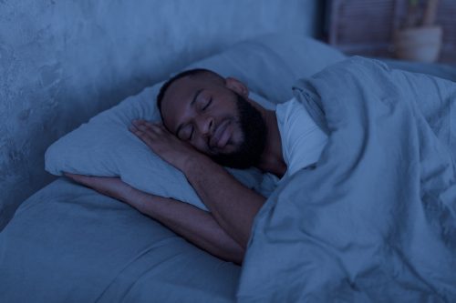 Chân dung người đàn ông trẻ người Mỹ gốc Phi hạnh phúc đang ngủ ngon lành trên giường với đôi mắt nhắm nghiền