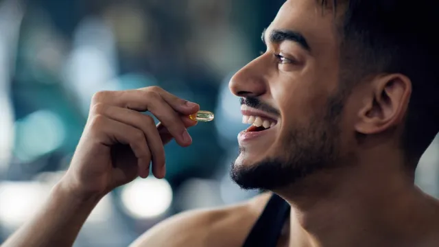 Portrait Of Happy Sportive Arab Man Taking Supplement Capsule,