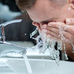 white man washing face in sink