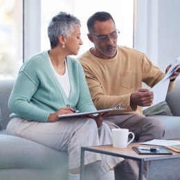 A middle-aged couple on their couch going over bills.