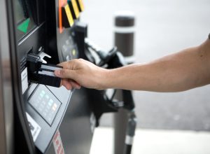 Close up of a person's arm using a credit card to pay for gas at a fuel pump