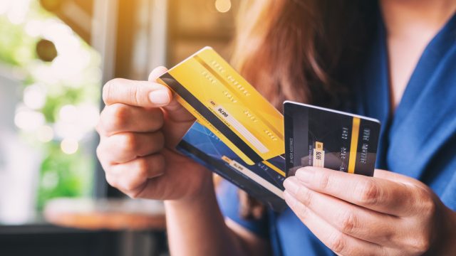 A closeup of a person holding three credit cards in their hand while pulling out one