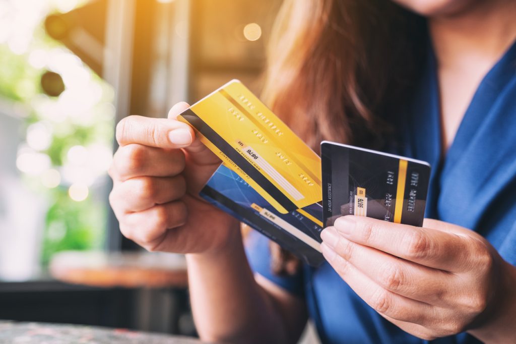 A closeup of a person holding three credit cards in their hand while pulling out one