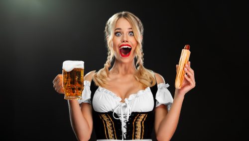 german woman in dirndl holding a beer and a hotdog